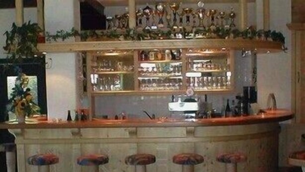 A bar area with stools, shelves of bottles, and decorative items. - Alpenhof (Sankt Martin am Tennengebirge)