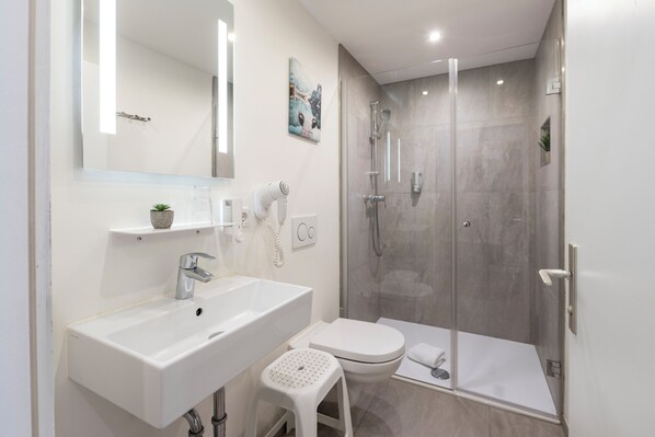 A modern bathroom with a white sink, toilet, and shower.