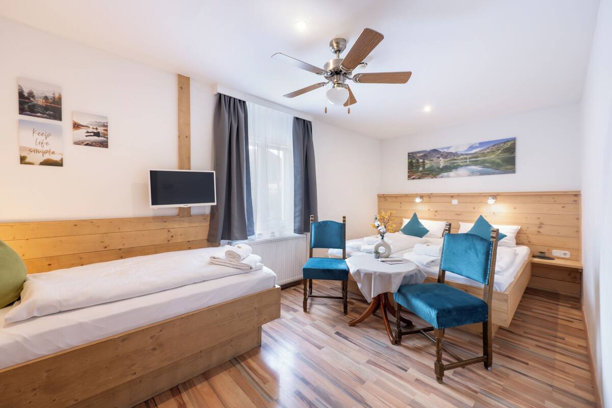 A hotel room with a bed, a desk, a chair, a television, and a ceiling fan.