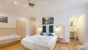 Een hotelkamer met een groot bed, een houten hoofdbord, een nachtkastje, een bureau, een spiegel en een zichtbare badkamer door een geopende deur.