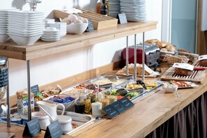 A buffet setup with various food items and serving utensils.