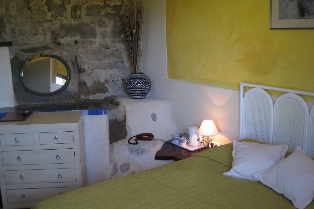 Une chambre à coucher avec un lit, une commode, une lampe et un vase.