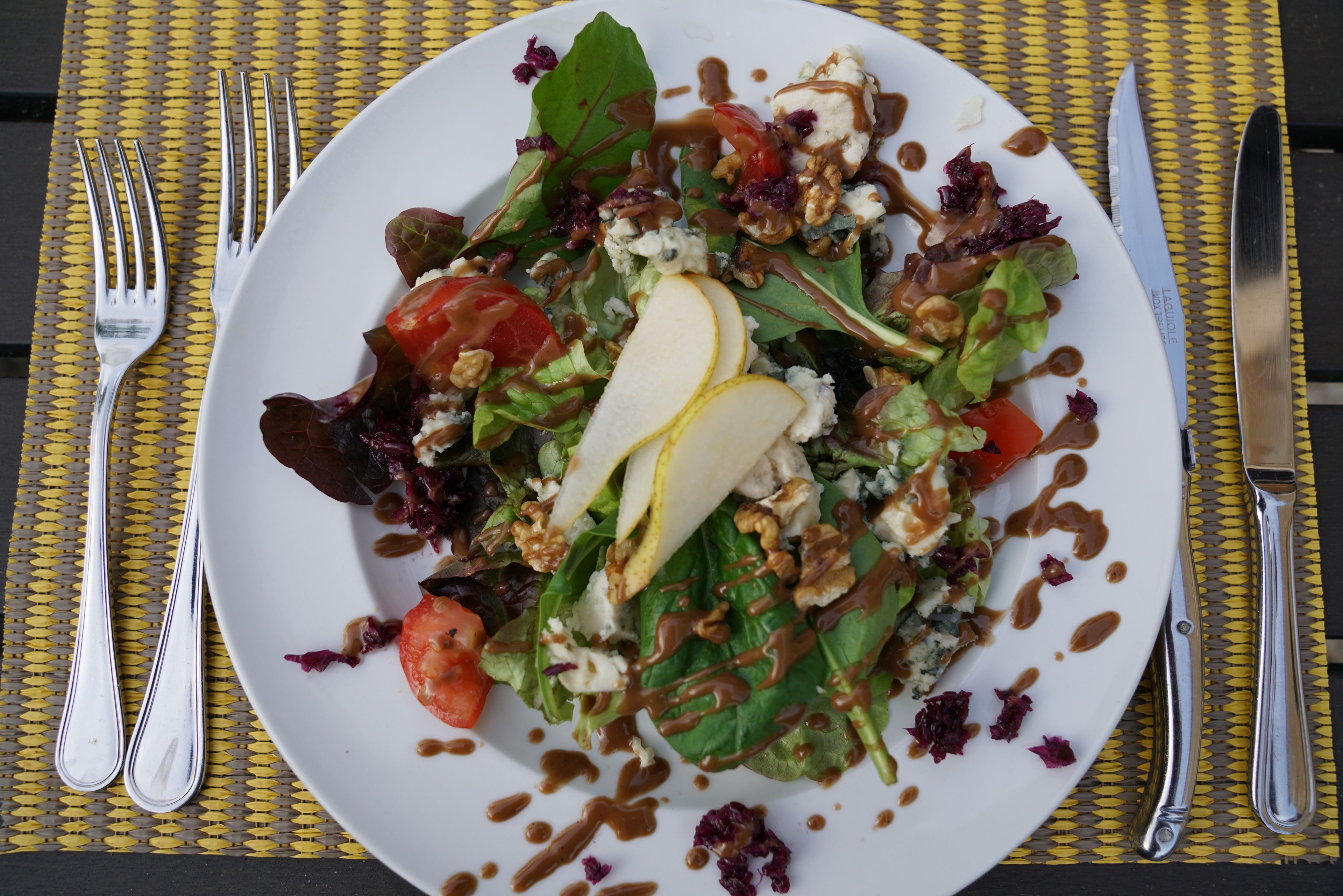 Une assiette de salade composée de divers ingrédients, arrosée d'une vinaigrette.