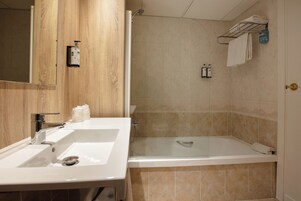 A bathroom with a wooden vanity, a bathtub, and a towel rack.