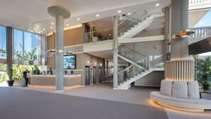 A spacious lobby with a reception desk, a staircase, and a seating area. - Ponient Dorada Palace by PortAventura World (Salou)