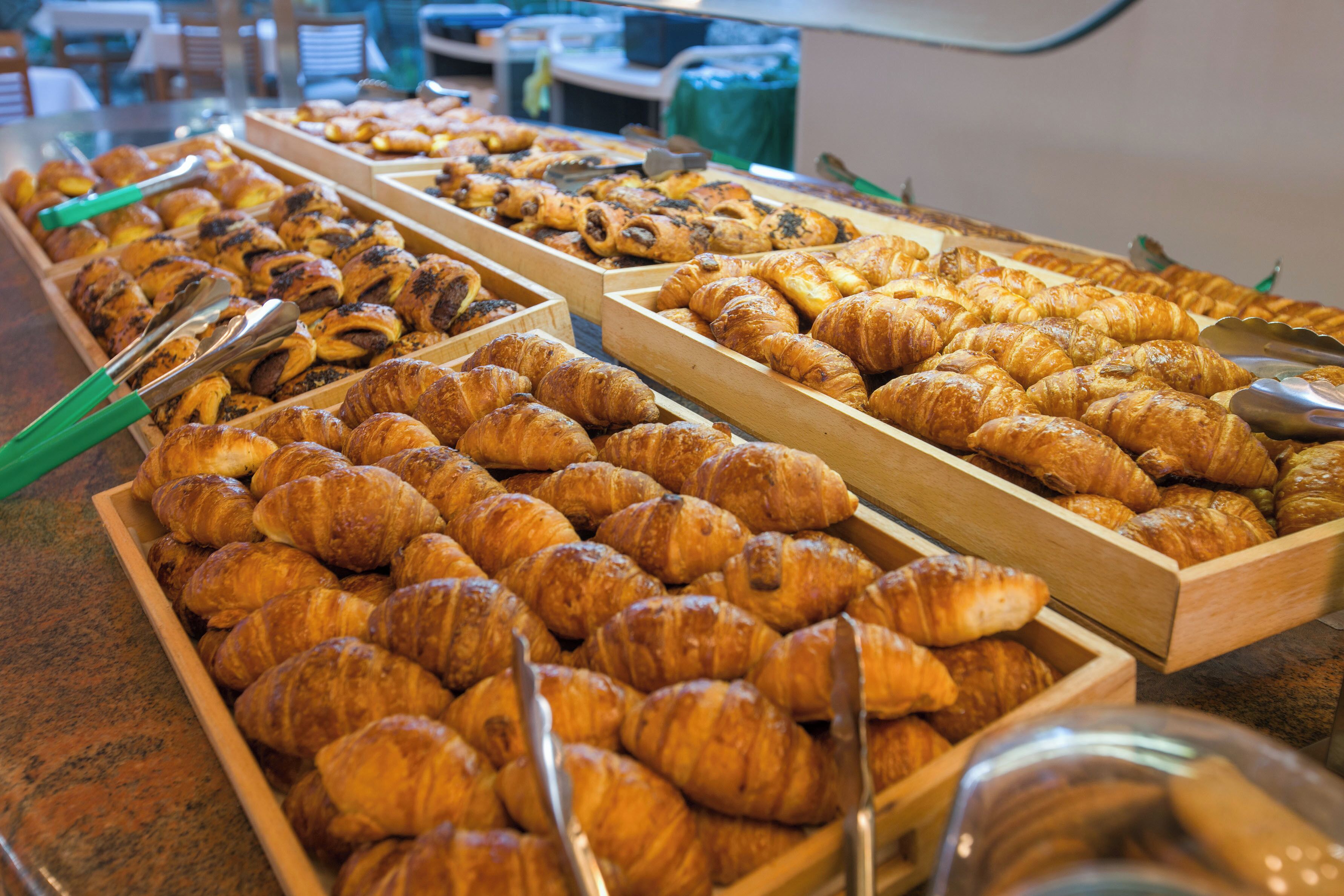 A variety of pastries displayed in wooden trays on a counter.