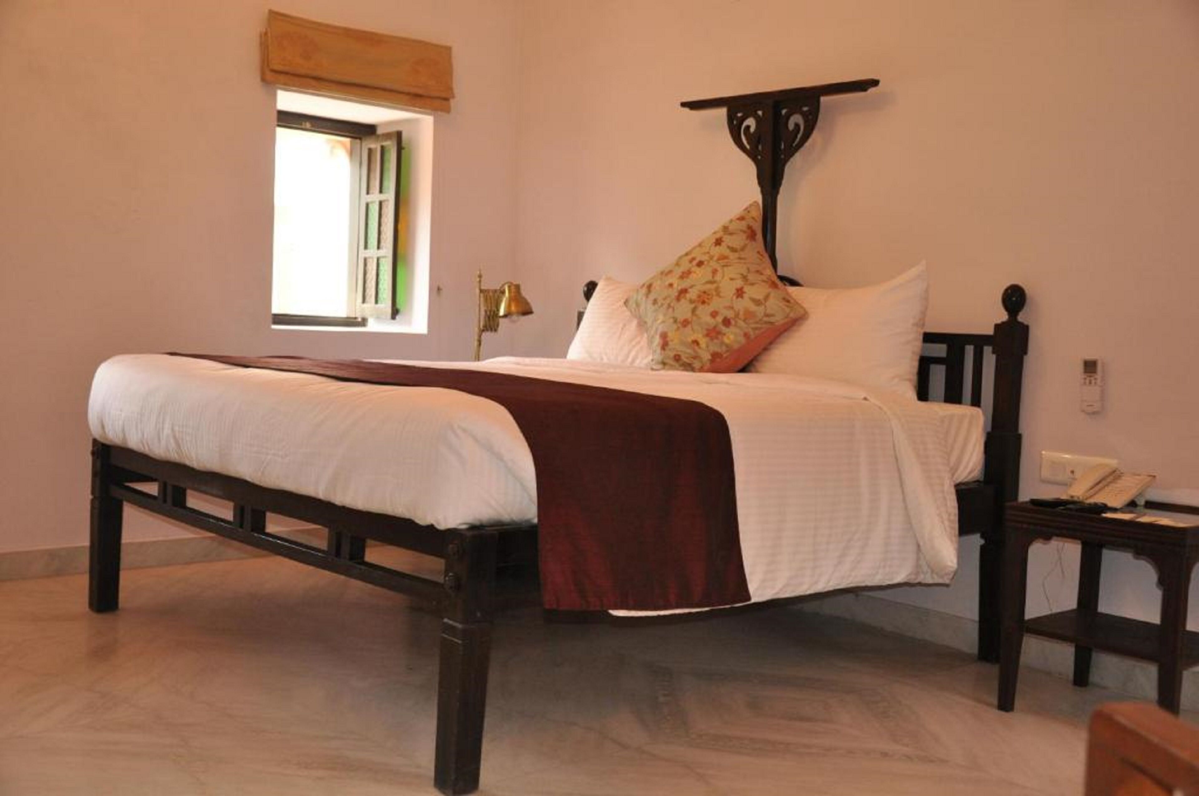 A bed with a headboard, a bedside table, a lamp, and a window with a view.