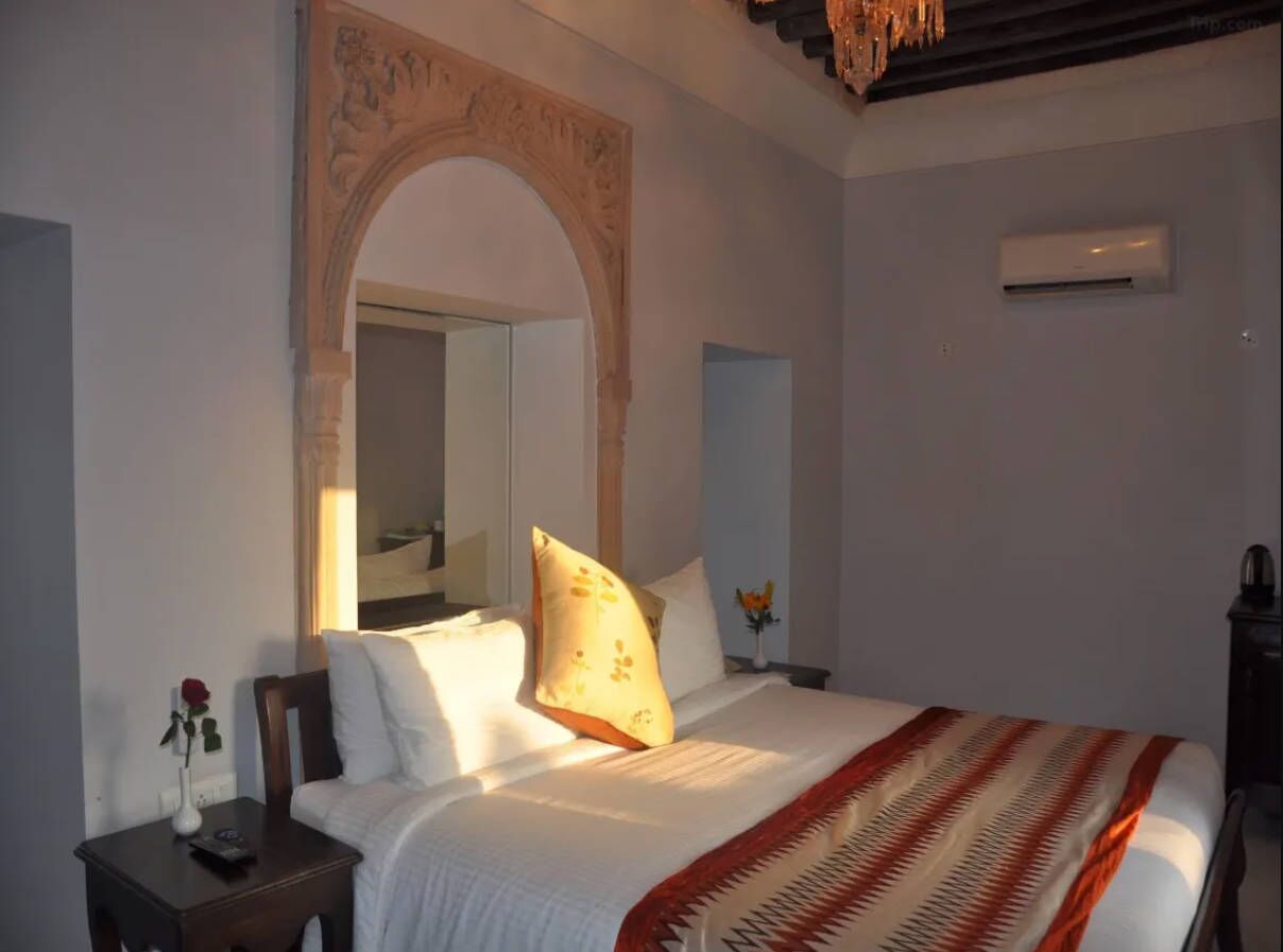 A bedroom with a bed, a nightstand, a mirror, and an arched doorway.