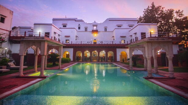 A hotel courtyard with a central pool, arched walkways, and a large building with multiple balconies. - Amritara Chandra Mahal Haveli (Nadbai)