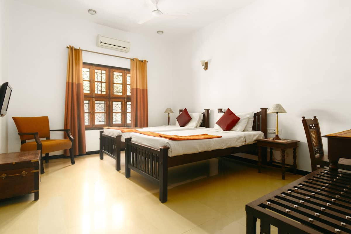 A hotel room with a bed, two chairs, a table, and a window with curtains.
