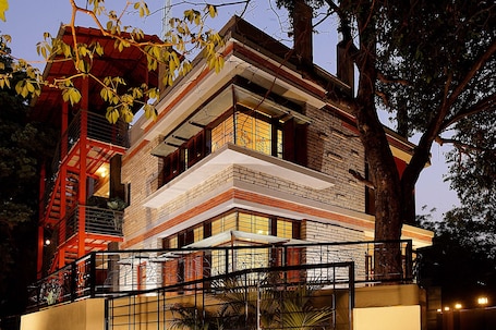 A multi-story building with a brick facade, large windows, and a balcony with a metal railing.