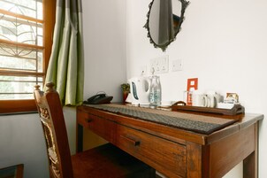 Een houten bureau met een telefoon, een waterkoker en een dienblad met kopjes en een mok.