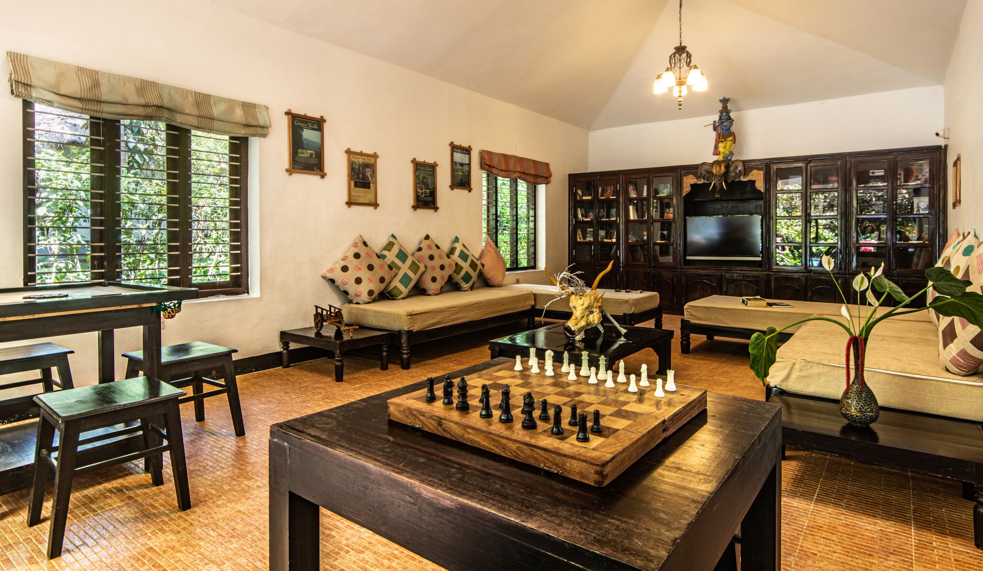 A cozy living room with a chessboard, a sofa, a TV, and a bookshelf.