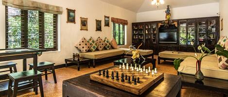 A cozy living room with a chessboard, a sofa, a TV, and a bookshelf.