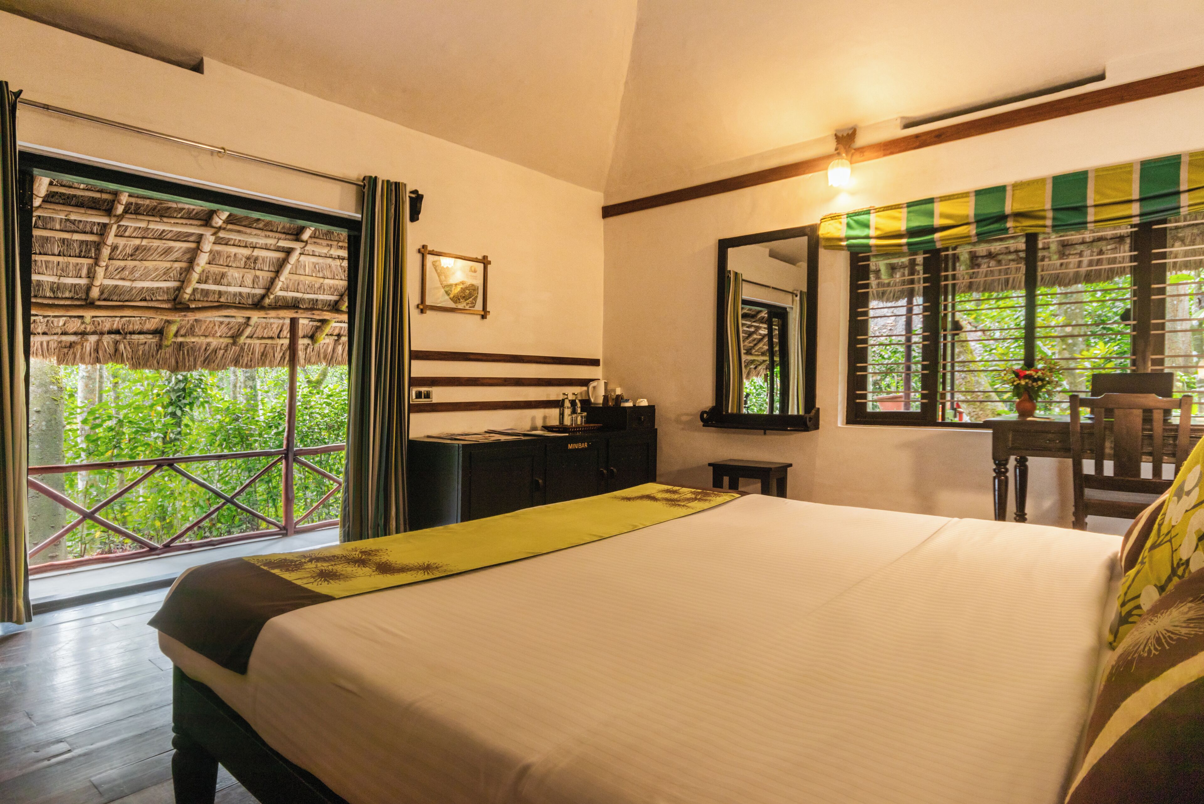 Habitación de hotel con una cama grande, un escritorio, una silla, un armario y una ventana con vista a áreas verdes.