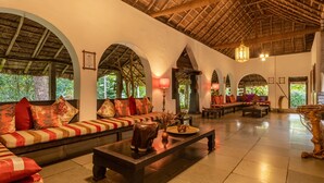 A spacious lobby with a high ceiling, thatched roof, and a seating area with sofas and armchairs. - Amritara Shalimar Spice Garden Resort & Spa (Peermade)