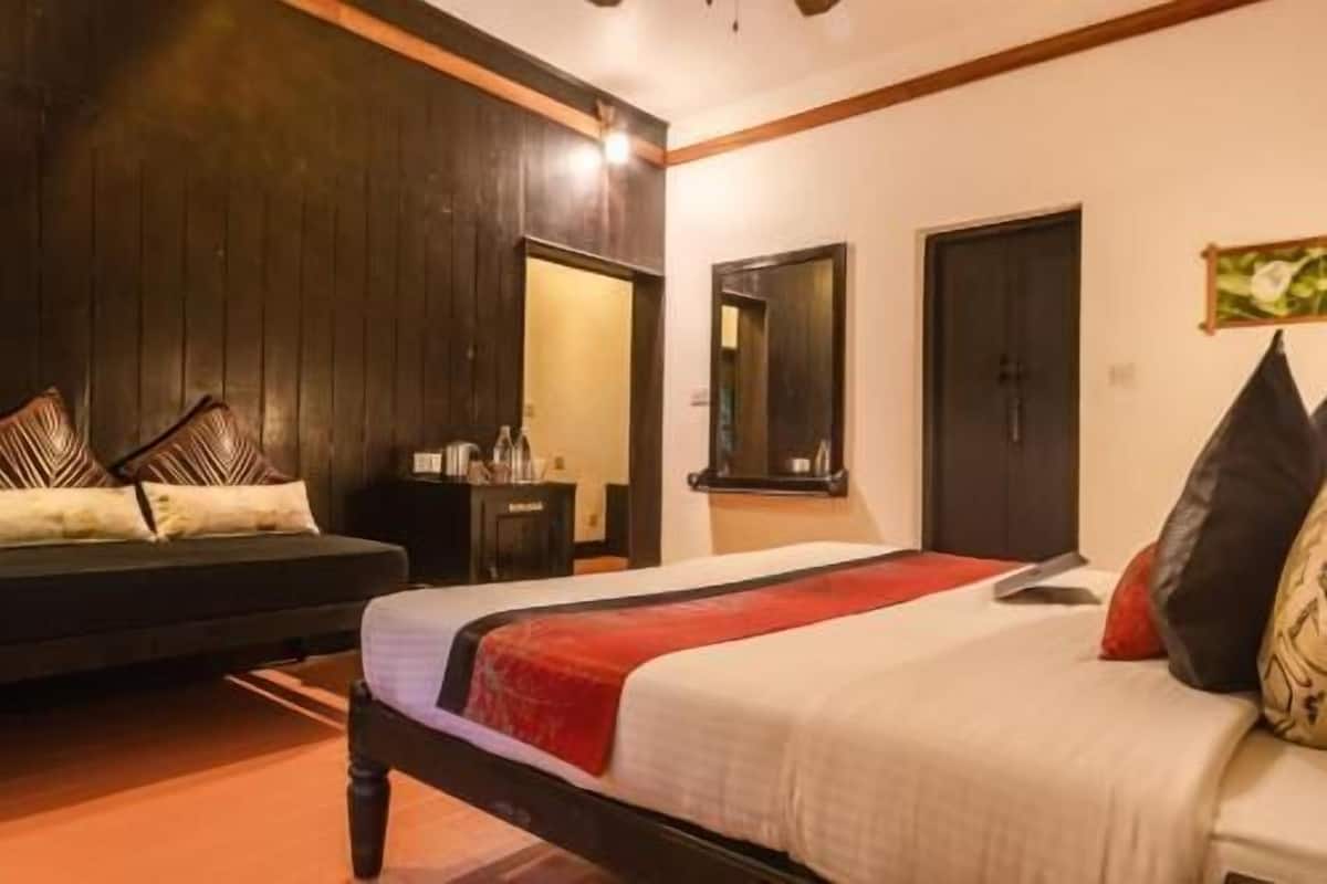 Ein Schlafzimmer mit Bett, Nachttisch, Kommode, Spiegel und Tür.