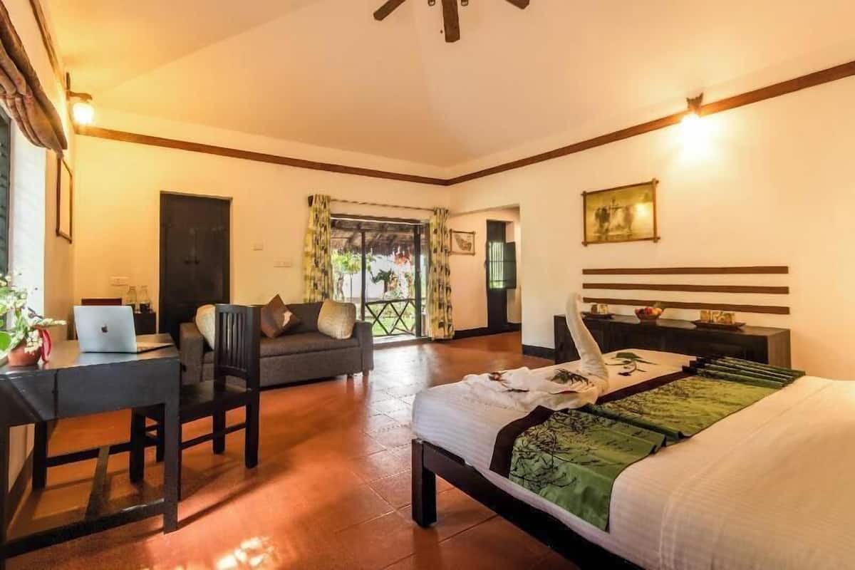 Ein Schlafzimmer mit einem Bett, einem Schreibtisch, einem Stuhl, einem Laptop, einem Fenster mit Vorhängen und einer Tür.