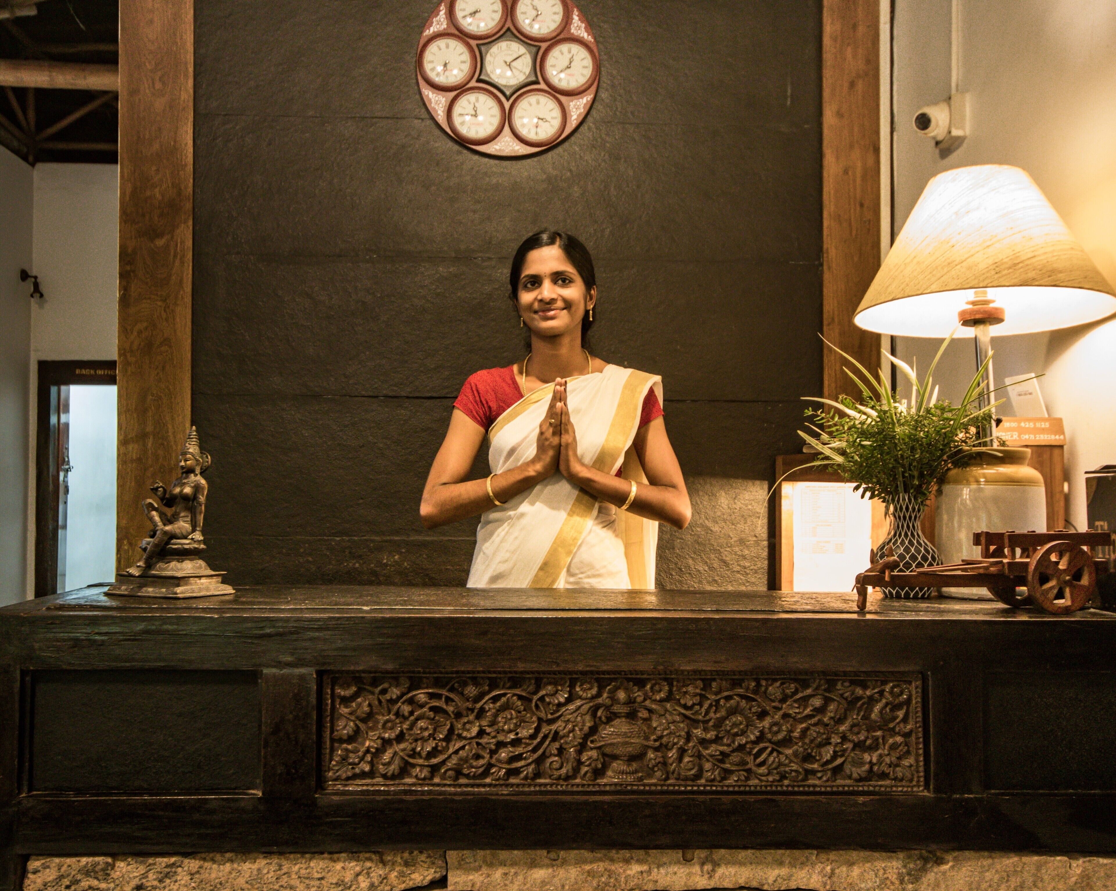 A reception desk with a clock, a lamp, and a statue.
