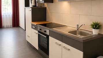 Una cocina moderna con horno empotrado, pileta de acero inoxidable y campana extractora negra.