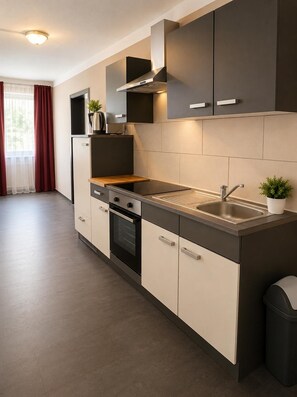 A modern kitchen with a built-in oven, a stainless steel sink, and a black range hood.