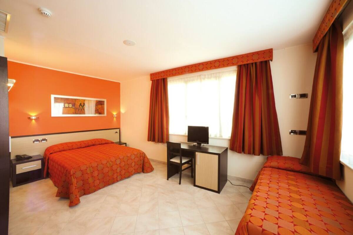Une chambre d’hôtel avec deux lits, un bureau et une télévision.