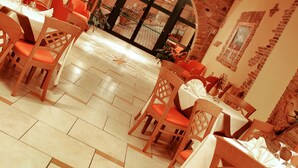 A restaurant with brick walls, wooden chairs, and tables set for dining. - Hotel Cristina (Rocca San Giovanni)