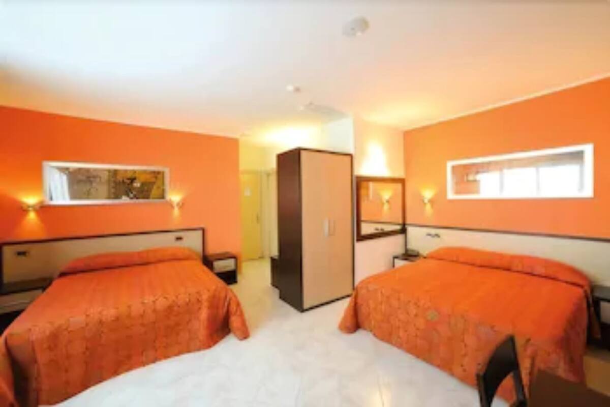 Une chambre d’hôtel avec deux lits, une armoire et un petit bureau.