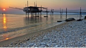 A beach with pebbles and a wooden structure extending into the water. - Hotel Cristina (Rocca San Giovanni)