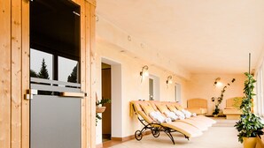Un espace spa avec des murs en bois, un sauna et des chaises longues.