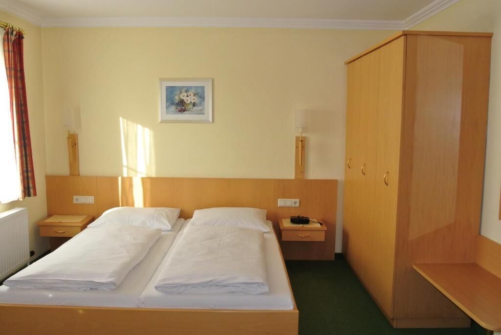 Quarto de hotel com cama de casal, duas mesas de cabeceira, um guarda-roupa e um quadro na parede.