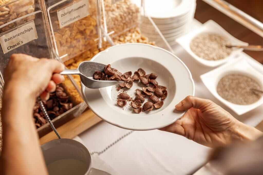A person scooping chocolate chips from a container into a bowl.