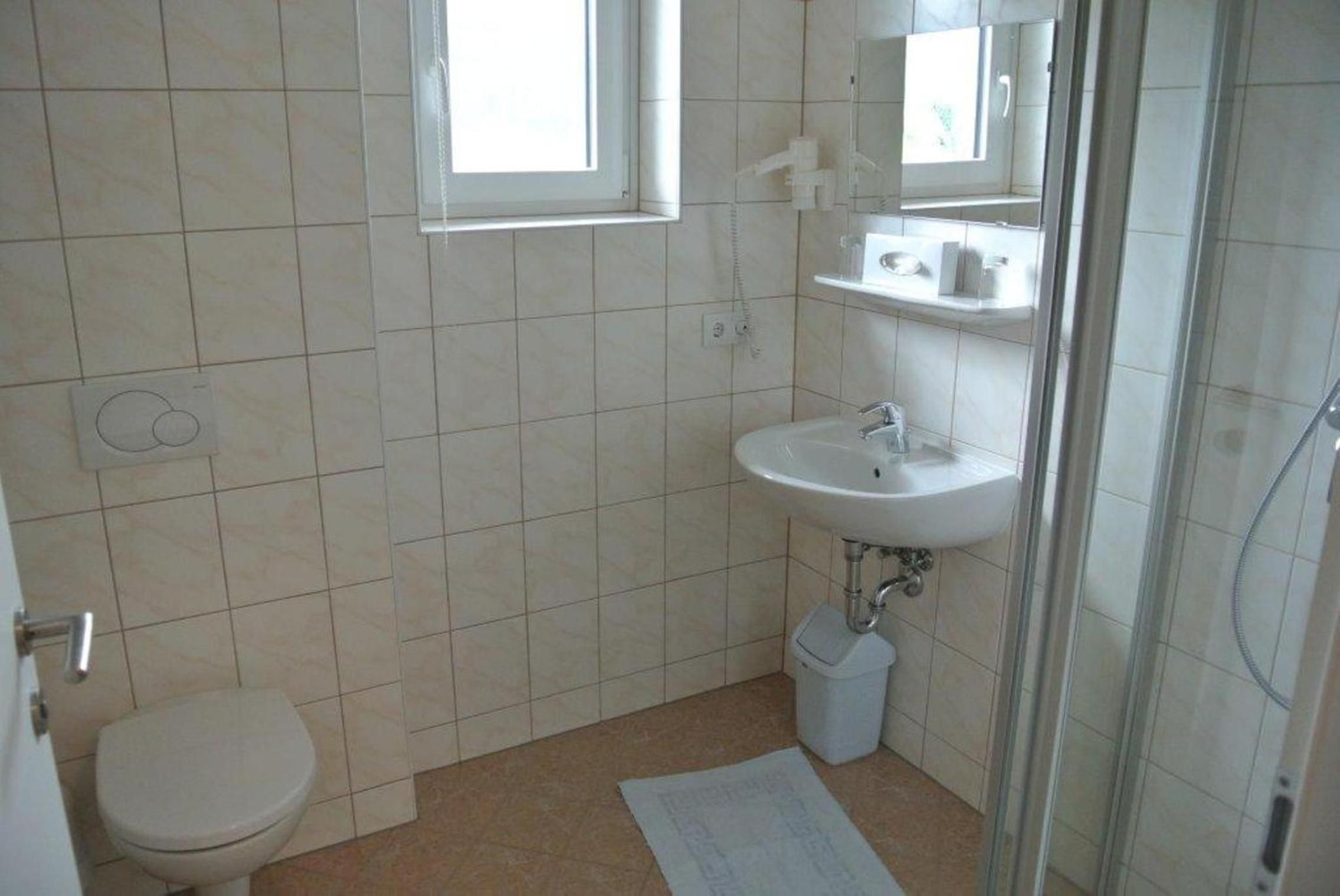 A small, clean bathroom with a toilet, sink, and shower.