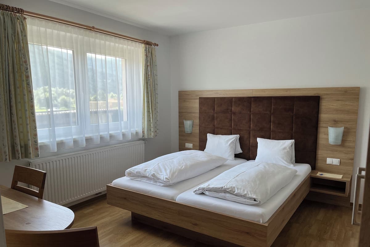 Una habitación de hotel con una cama y una mesa de madera, además de sillas.
