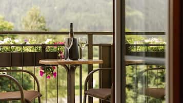 Ein Balkon mit Tisch, zwei Stühlen, einer Flasche und zwei Gläsern.