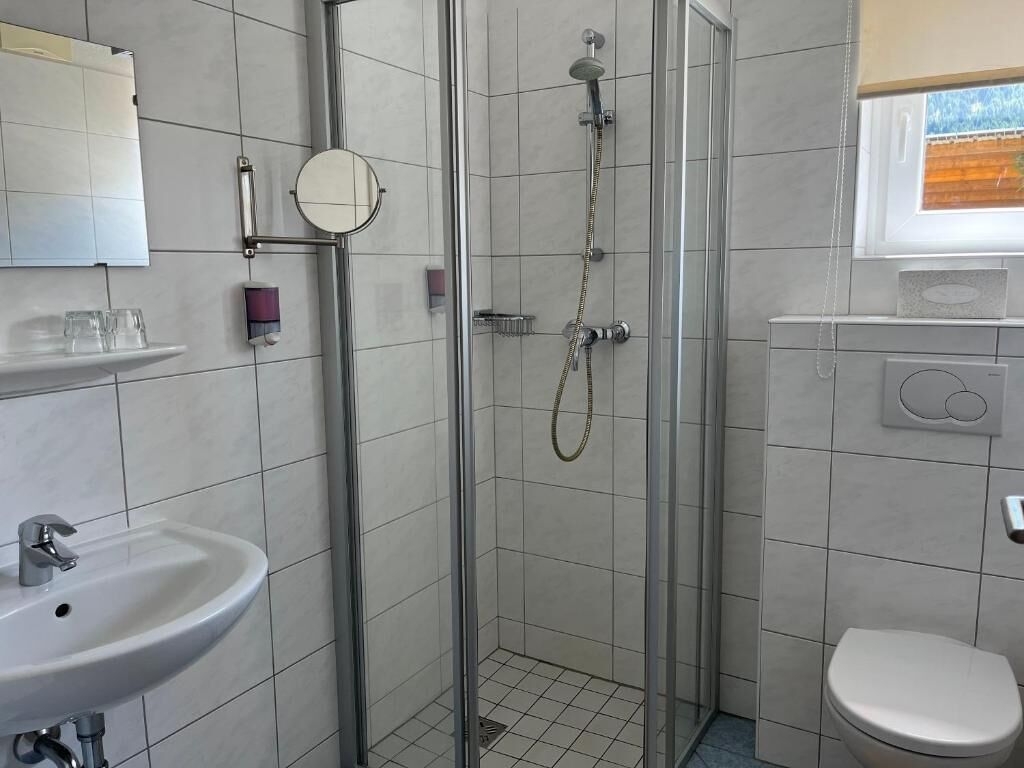 Ein Badezimmer mit Dusche, Waschbecken, Toilette und einem Fenster.