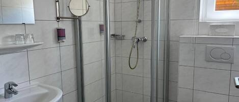 A bathroom with a shower, sink, toilet, and a window.