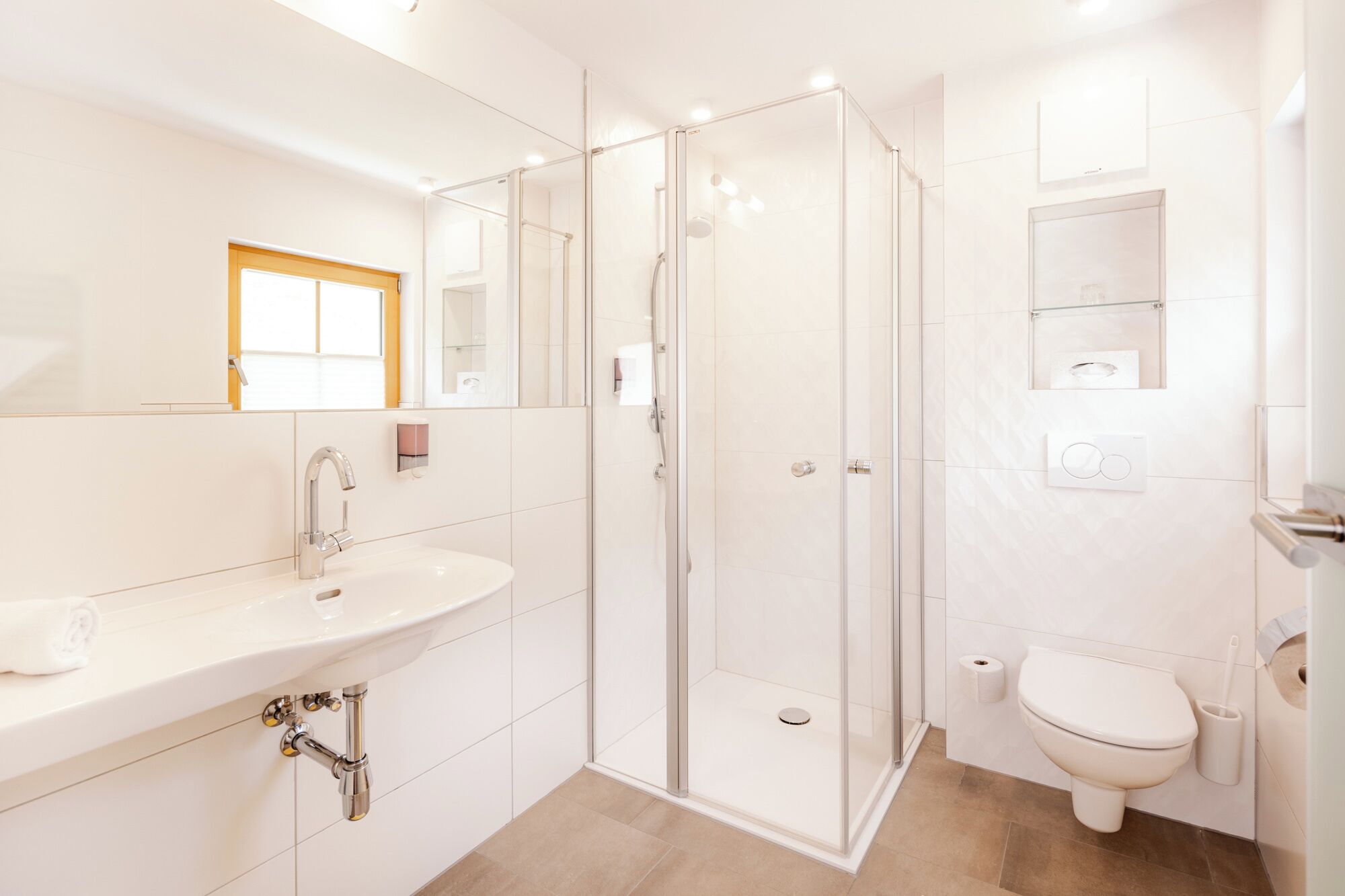 Un baño moderno con ducha envuelta en vidrio, un lavabo con espejo y un inodoro.