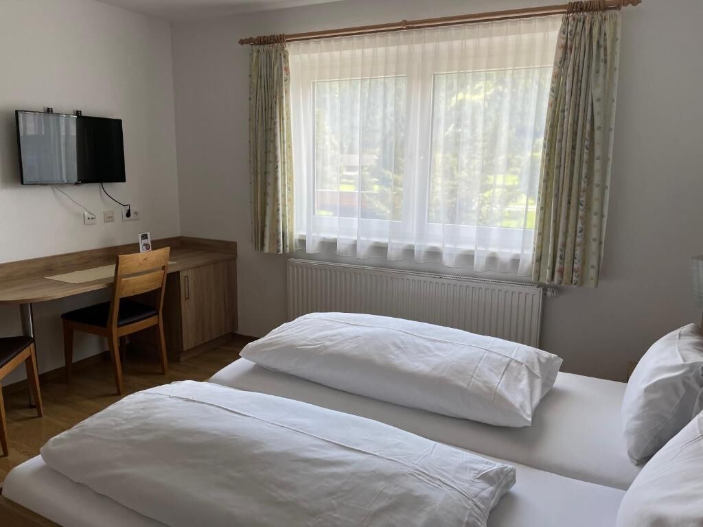 Une chambre d’hôtel avec un lit, un bureau et une télévision.