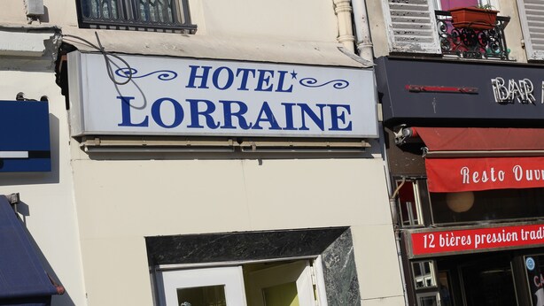 A building with a sign for HOTEL LORRAINE and a bar with a red awning. - Hôtel De Lorraine (Paris)