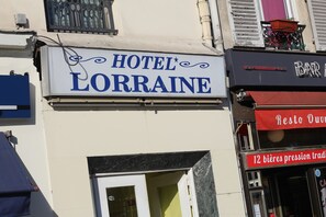A building with a sign for HOTEL LORRAINE and a bar with a red awning. - Hôtel De Lorraine (Paris)