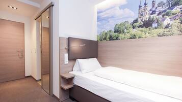 A modern bedroom with a large bed, a nightstand, and a wall-mounted lamp.