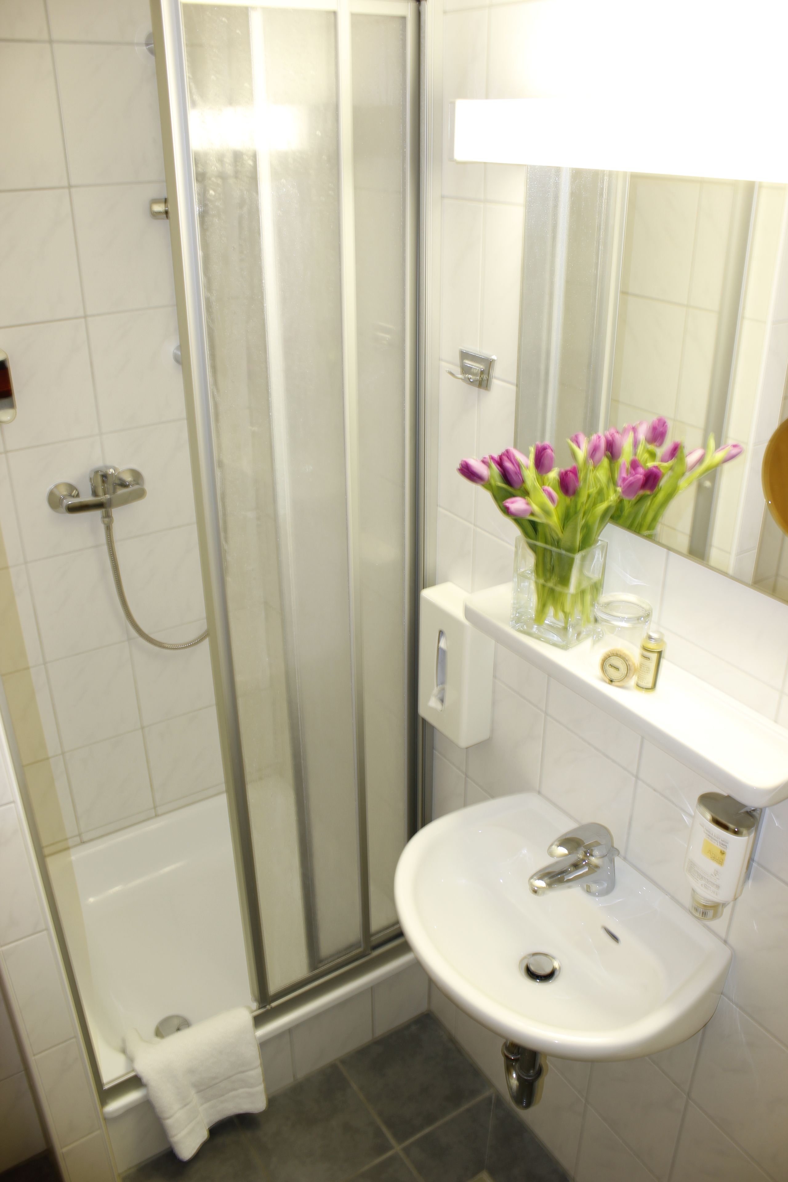 A bathroom with a glass shower enclosure, a white sink, and a mirror above the sink.