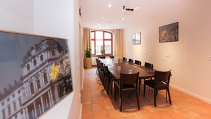 A conference room with a long table, chairs, a projector, and a window with curtains. - City Hotel Würzburg (Würzburg)