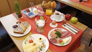 A breakfast buffet with various food items and a small plant on the table. - City Hotel Würzburg (Würzburg)