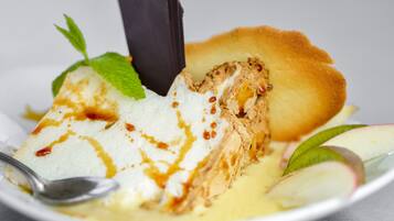 Ein Dessert mit einer Kugel Eis, einem Kuchenstück und Apfelscheiben auf einem Teller.