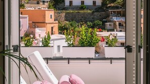 A balcony with a white lounge chair, pink cushions, and potted plants. - Villa Mary Suites (Positano)