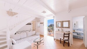 A white interior with a staircase, a sofa, a dining area, and a view through an open door. - Villa Mary Suites (Positano)