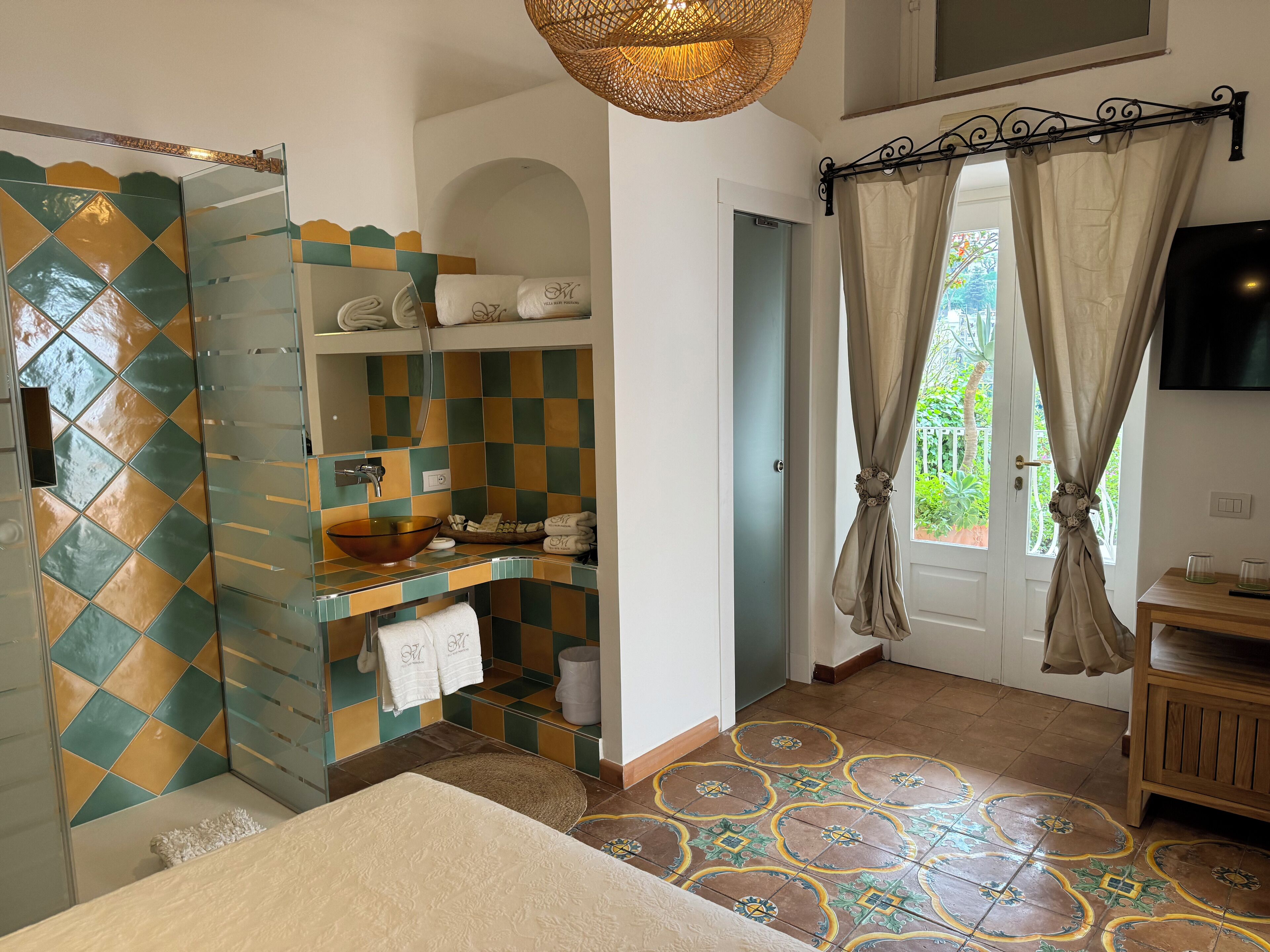 A bathroom with a checkered tile backsplash, a glass sink, and a shower area.