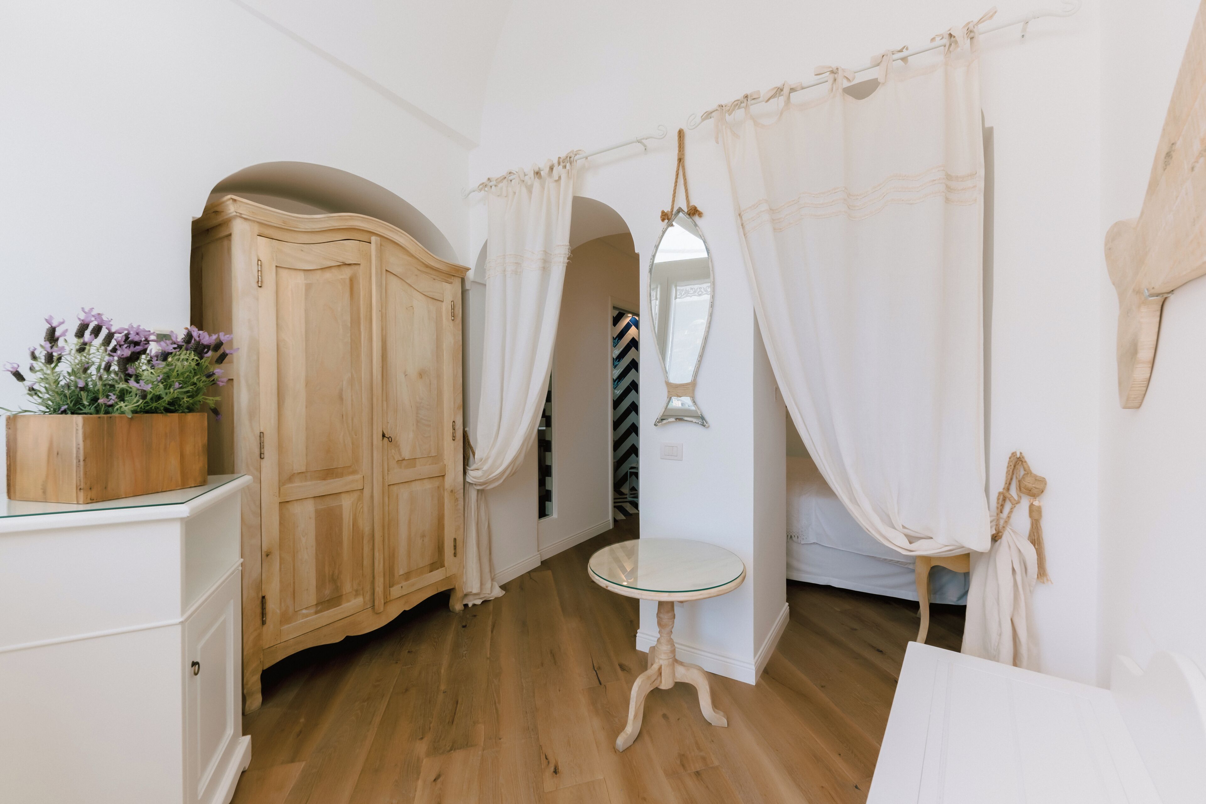 Una habitación con un armario de madera, una mesa redonda pequeña y un espejo en la pared.